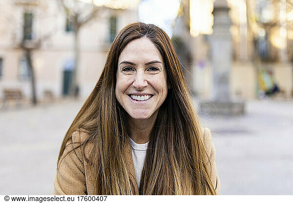 Happy woman with long brown hair in city