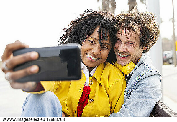 Happy woman with man taking selfie through smart phone