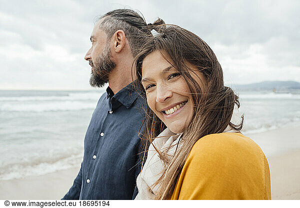 Happy woman with mature man standing in front of sea