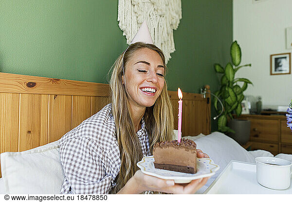 Happy woman with piece of cake enjoying birthday at home