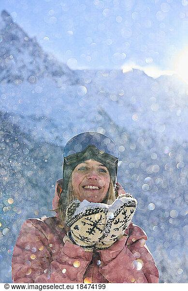 Happy woman with snow standing in front of mountain