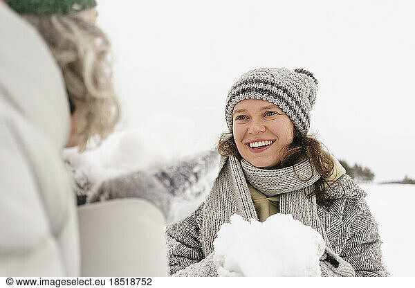 Happy woman with snowball looking at friend