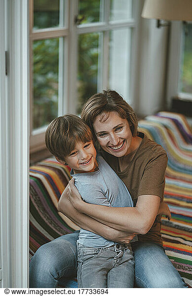 Happy woman with son sitting on sofa at home
