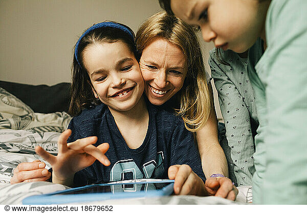Happy woman with sons using digital tablet at home