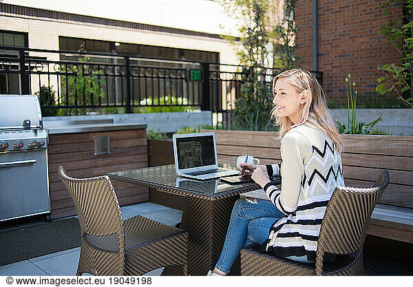 Happy woman working on computer outdoors on patio