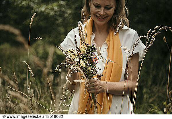 Happy womanwith bunch of wildflowers in field