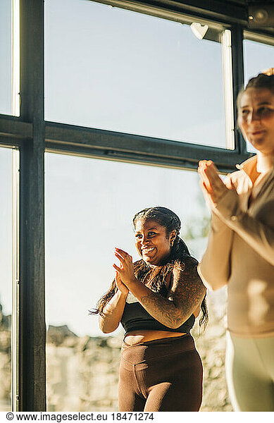 Happy women clapping during yoga class at retreat center