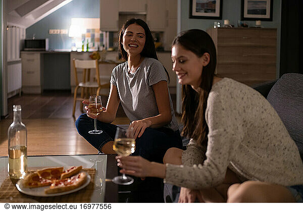 Happy women communicating during wine party on couch