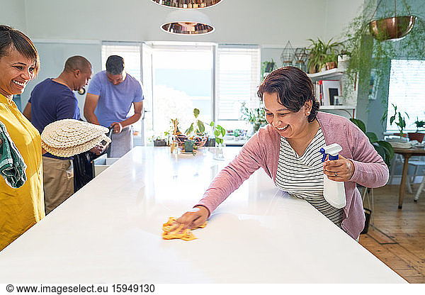 Happy women friends cleaning kitchen island