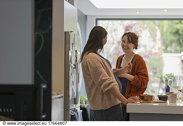 Happy women friends eating cake in kitchen