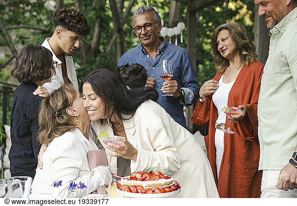 Happy women hugging each other during midsummer dinner party