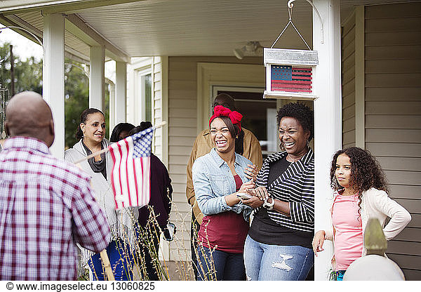 Happy women looking at man with American flag outside house