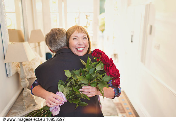 Happy women receiving rose bouquet and hugging husband