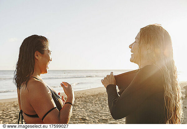 Happy women taking off wetsuit after surfing at beach on sunset  Gran Canaria  Canary Islands