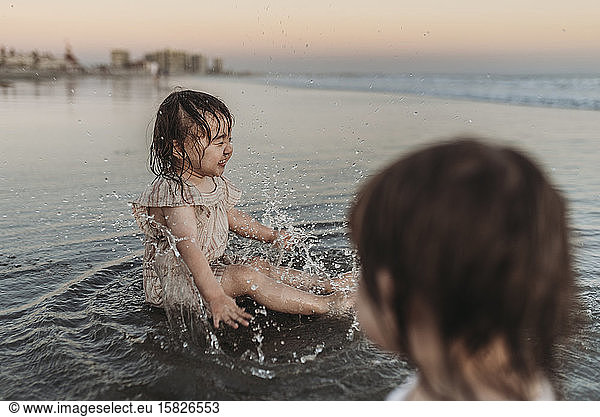 Happy 2 year old girl splashing in water at beach