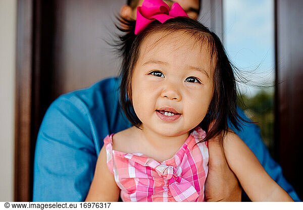 Happy young asian girl with brown eyes and pink bow in hair