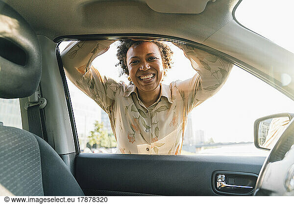Happy young businesswoman looking through car window