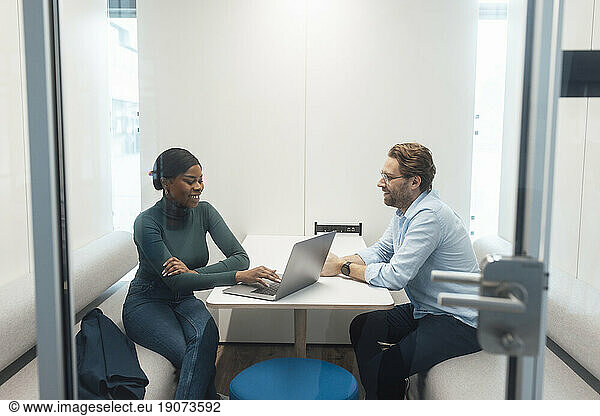 Happy young businesswoman talking to client in office