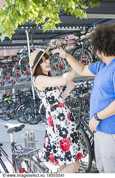 Happy young couple dancing in city by bicycle parking