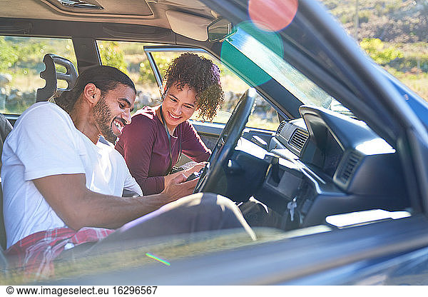 Happy young couple enjoying road trip in sunny car