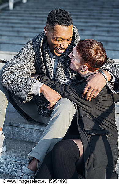 Happy young couple hugging on stairs in the city