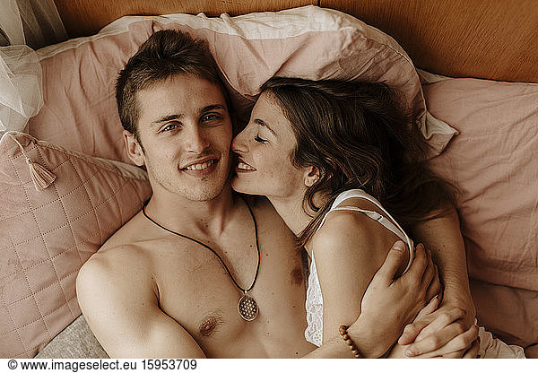 Happy young couple lying in bed