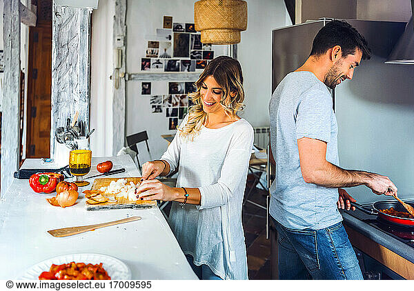 Happy young couple preparing food together in kitchen at home