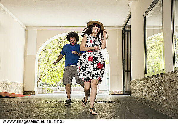 Happy young couple running in building corridor