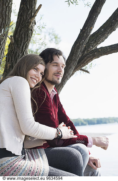 Happy young couple sitting lake