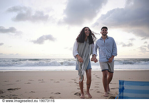Happy young couple standing on sand at beach