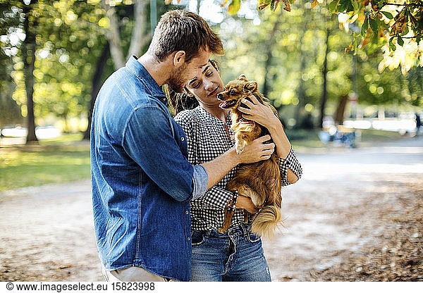 Happy young couple with dog in a park