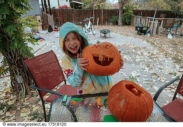 Happy young girl showing off her carved pumpkin