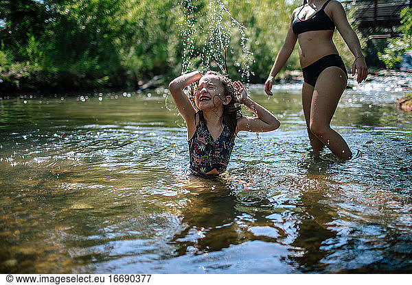 Happy young girl splashing in a creek on a warm day