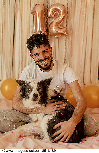 Happy young man celebrating border collie dog's birthday