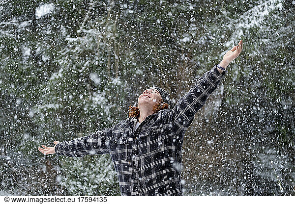 Happy young man in warm clothing enjoying snowfall