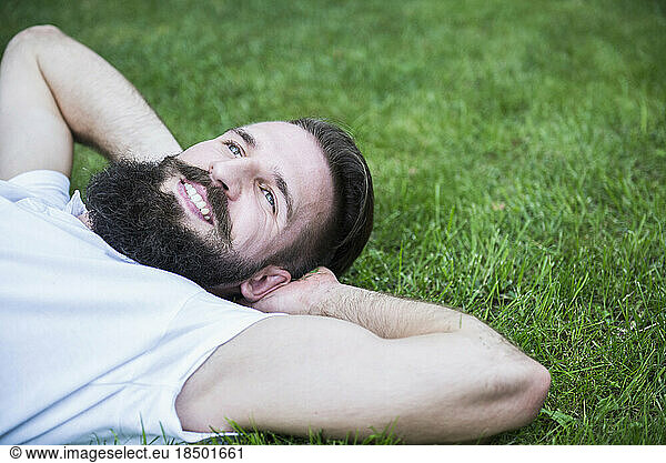 Happy young man lying in garden  Bavaria  Germany