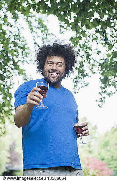 Happy young man outdoors with glass of wine
