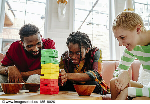 Happy young man playing block removal game with friends