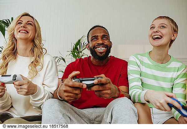 Happy young man playing video game with friends at home