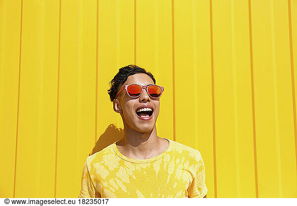 Happy young man screaming in front of yellow wall