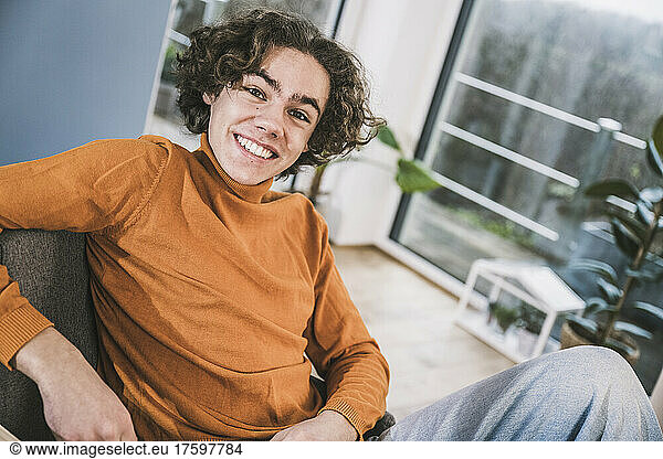 Happy young man sitting in living room at home