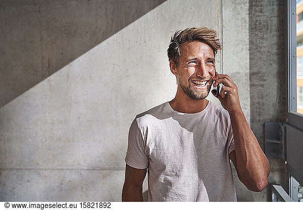 Happy young man wearing t-shirt talking on the phone