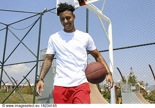 Happy young man with basketball at sports court