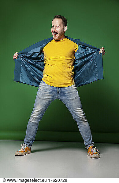 Happy young man with mouth open standing against green background