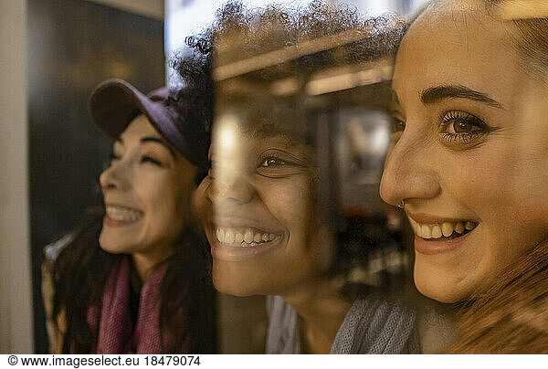 Happy young multiracial friends seen through glass