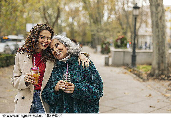 Happy young woman arm around with grandmother at footpath