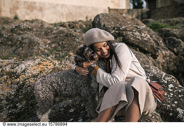Happy young woman cuddling her dog in the city