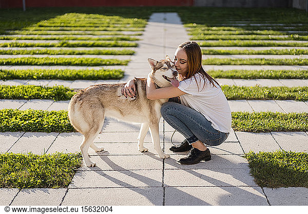 Happy young woman cuddling her dog outdoors