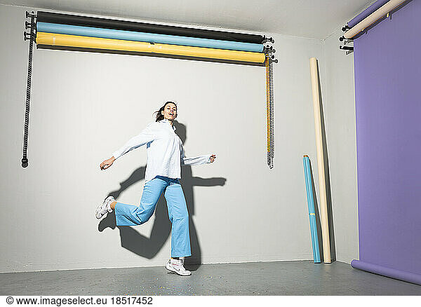 Happy young woman dancing in front of wall