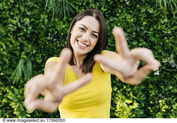 Happy young woman gesturing peace sign